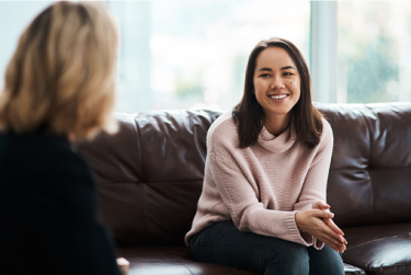 Duas mulheres sentadas, uma em frente para a outra, conversando